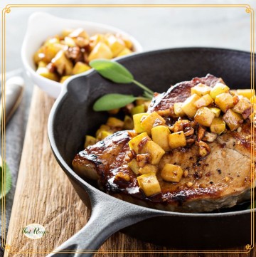 pork chops with apples on top in a cast iron skillet