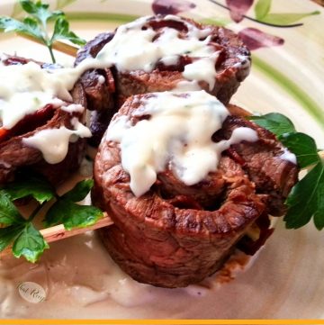 close up off grilled roll of beef stuffed with bacon covered in sauce