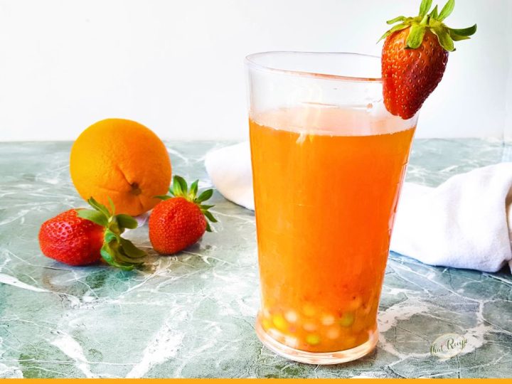 glass of berry orange boba tea with strawberries and orange in background