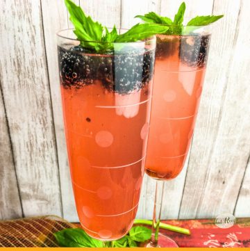glass of pink sparkling punch with blackberries and basil