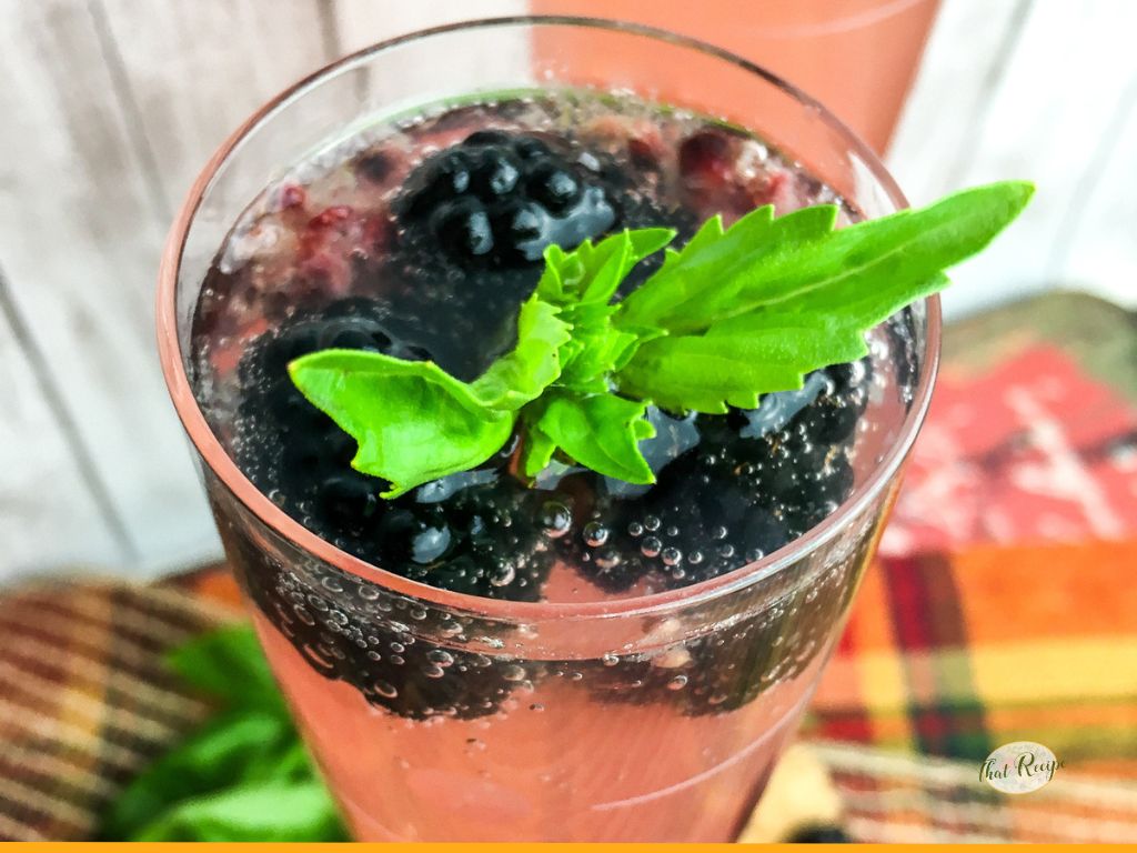 glass of pink sparkling punch with blackberries and basil