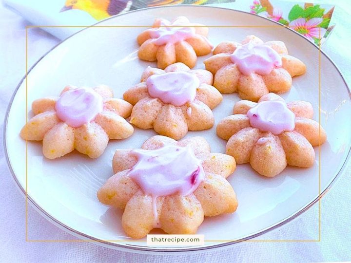 orange spritz cookies with pink frosting on a plate