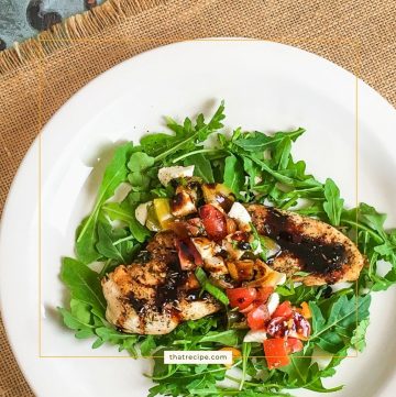 chicken breast topped with tomatoes and mozzarella on a bed of arugula
