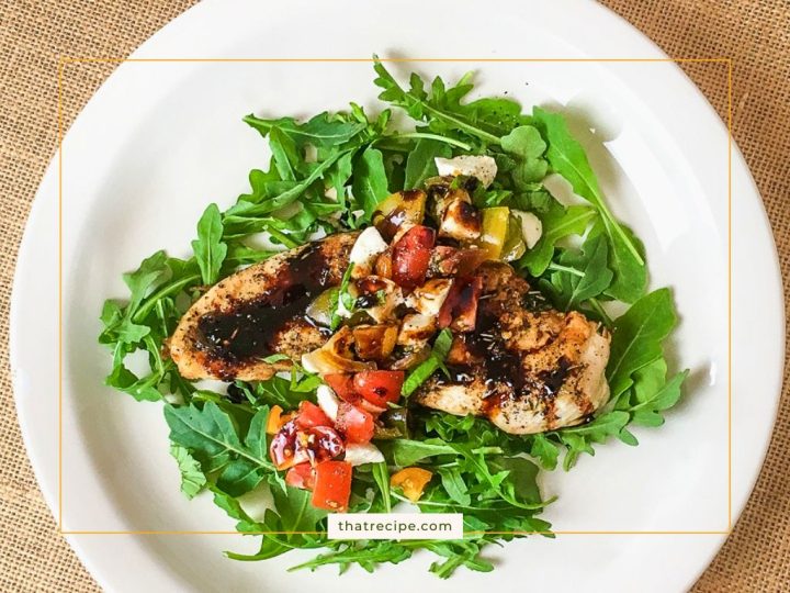 chicken breast topped with tomatoes and mozzarella on a bed of arugula