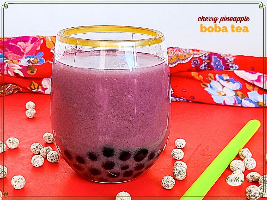 glass of bubble tea surrounded by uncooked tapioca pearls and text overlay "cherry pineapple boba tea"
