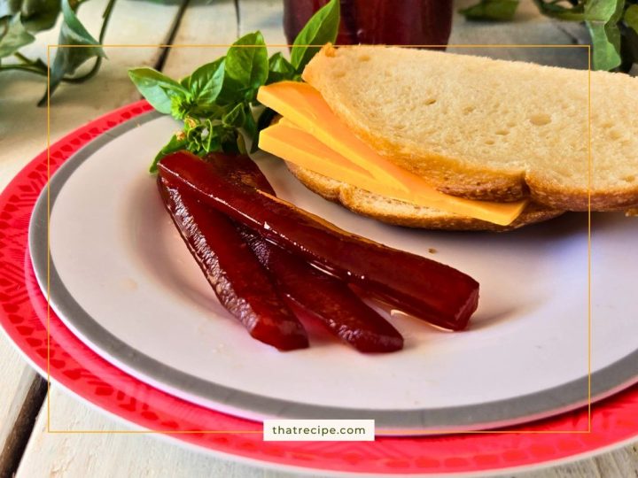 red pickle spears on a plate with a sandwich