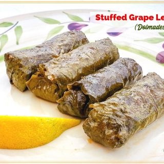 4 dolmades on a plate with a slice of lemon and text overlay "Stuffed grape leaves (dolmades)