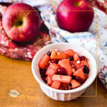 cranberry apple compote in a cup with fresh apples