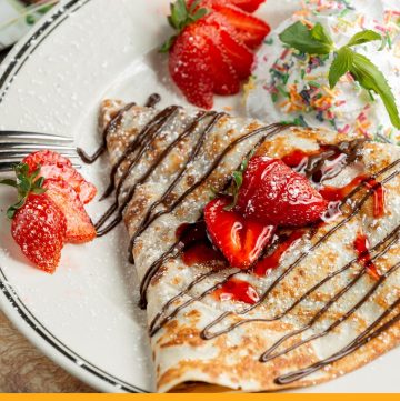 crepe on a plate with chocolate and strawberries on top and text overlay Basic crepes