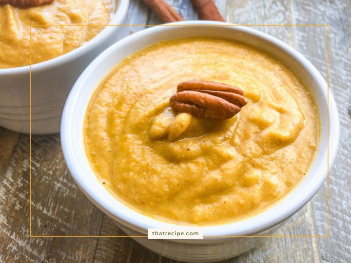 Bowl of pureed soup topped with a pecan