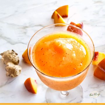 wine slushie on a marble backdrop with frozen peaches and ginger