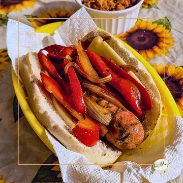 Italian sausage and pepper sandwich on a table with baked beans