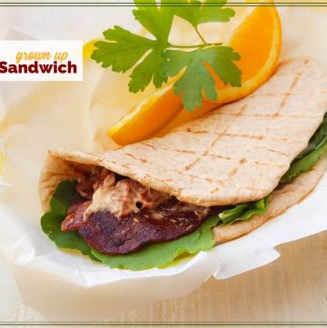 BLT pita wrap with orange slices and text overlay "grown Up BLT Sandwich"