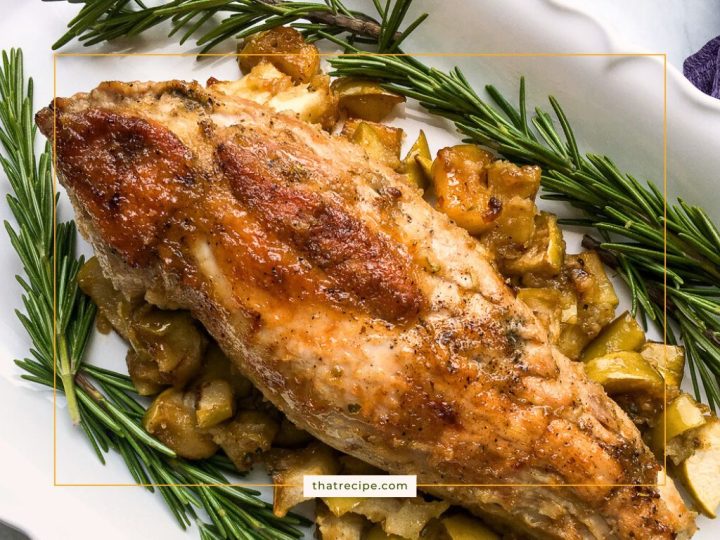 pork tenderloin on a plate with fresh rosemary and roasted apples