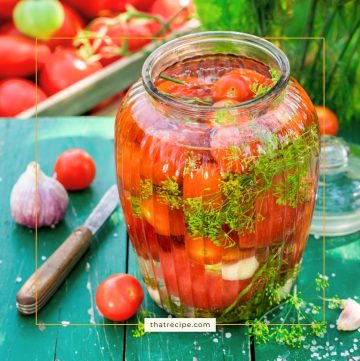 cherry tomatoes in a jar with fresh herbs, garlic and liquid