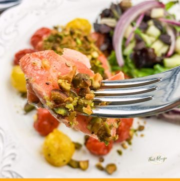 fork holding a piece of pistachio covered salmon
