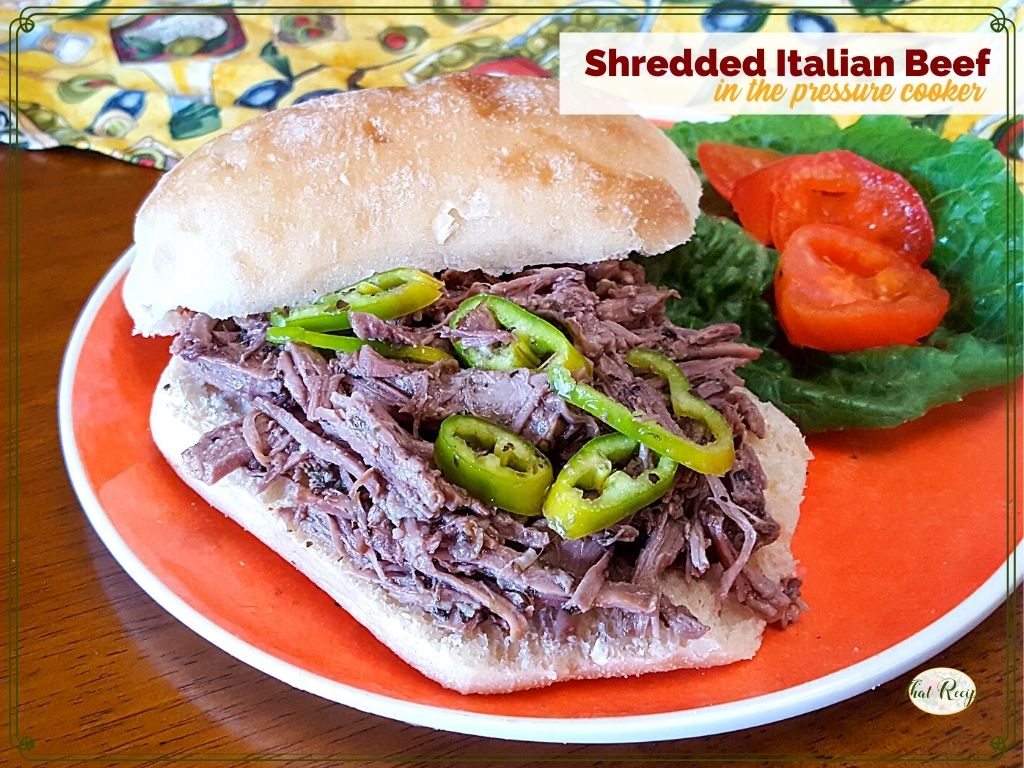 shredded beef sandwich on a plate with lettuce, tomatoes and peppers with text overlay "Shredded Italian Beef in the pressure cooker"