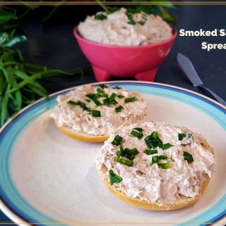 smoked salmon spread on a bagel with a bowl of smoked salmon spread in a pink bowl.