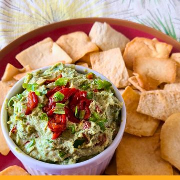green and red hummus in a bowl with pita chips and text overlay "spinach and red pepper hummus"