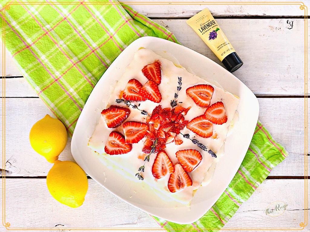 square cake topped with fresh strawberries and fresh lavender blossoms