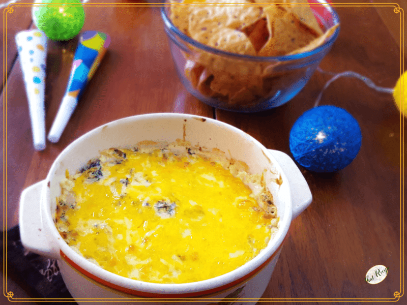 cheesy kale dip and chips on a table with party favors