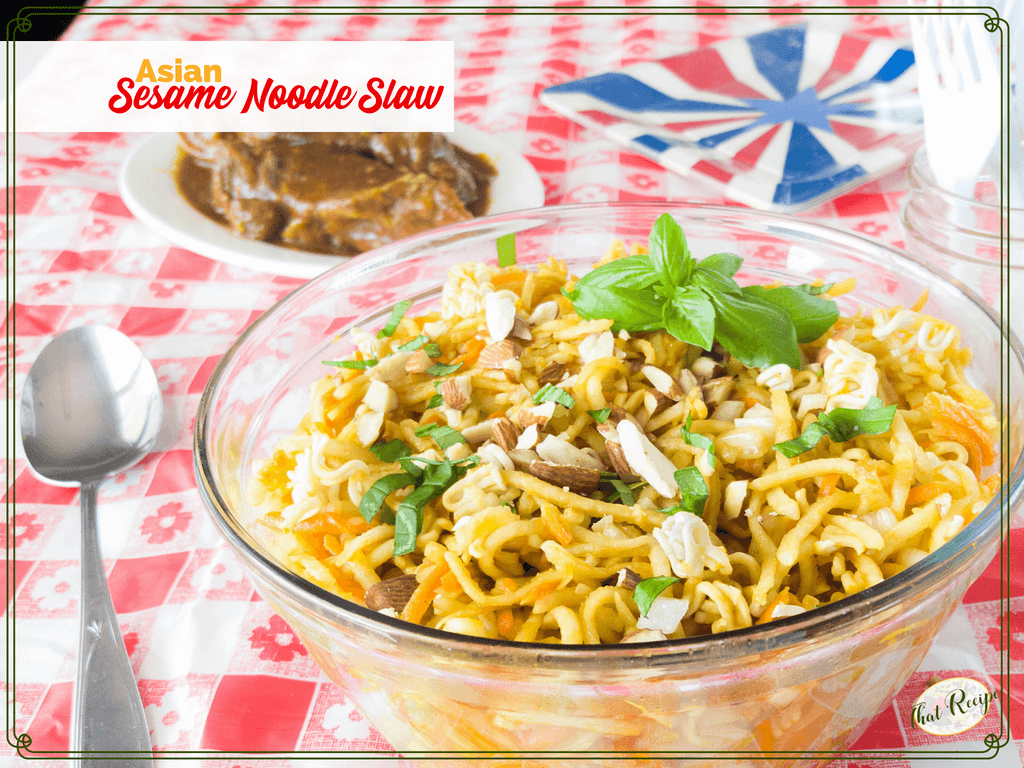 bowl of Asian slaw on a picnic table with text overlay "Asian Sesame Noodle Slaw"